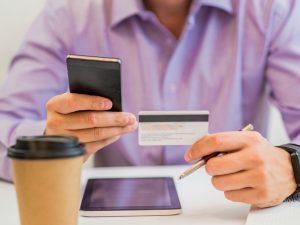 hombre pagando su tarjeta de crédito en su celular