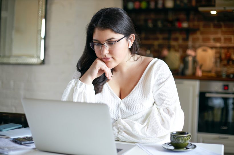 mujer concentrada revisando algo en su laptop