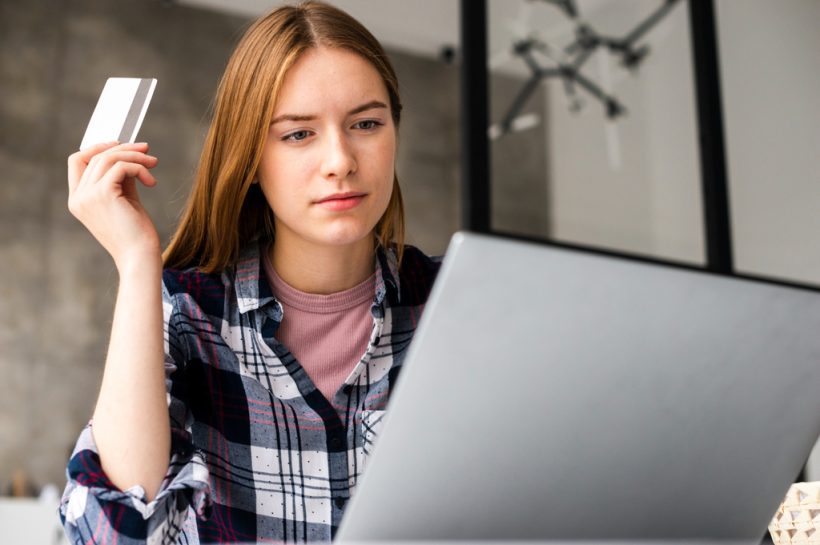 mujer concentrada revisando información de su tarjeta de crédito