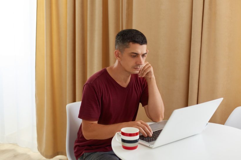 hombre dubitativo revisando una información en su laptop